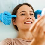 This Is A Photo Of A Woman Who Has Just Received A Facelift And Is Admiring The Results In A Mirror.